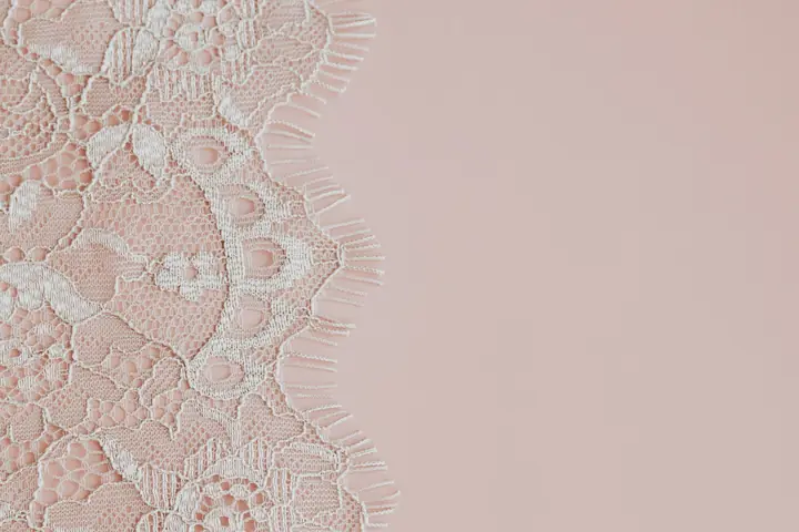 Dentelle blanche sur fond rose poudré