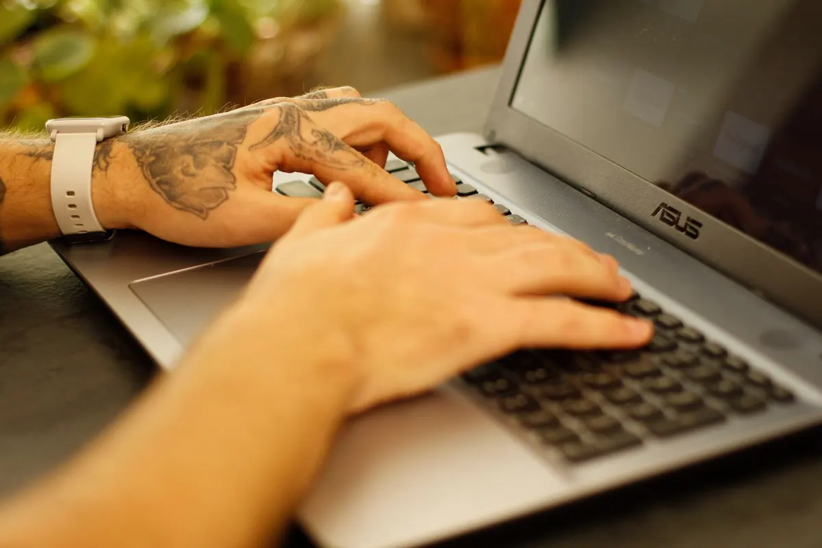 Mains tatouées sur un clavier, en illustration de « acheter des sous-vêtements usés »