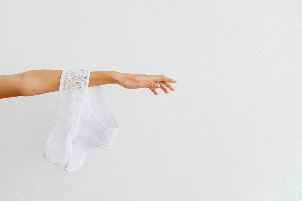 Culotte en dentelle blanche tenue d'une main, en illustration de « strings souillés »