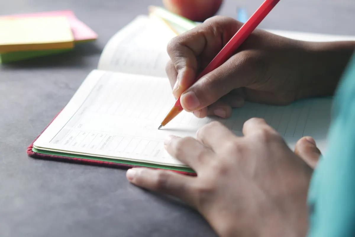 Crayon rouge sur un cahier, en illustration de « ce que les meilleures vendeuses ont en commun »