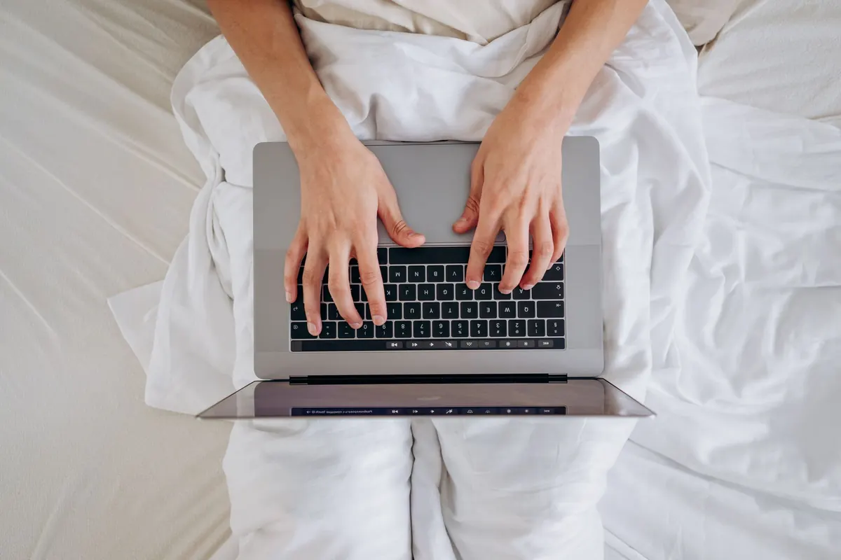 Mains sur un ordinateur dans le lit, en illustration de « pourquoi les culottes portées excitent »