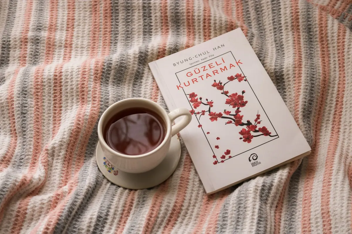 Tasse de thé et livre sur un drap rayé, en illustration de « acheteur de culottes en quartier populaire »