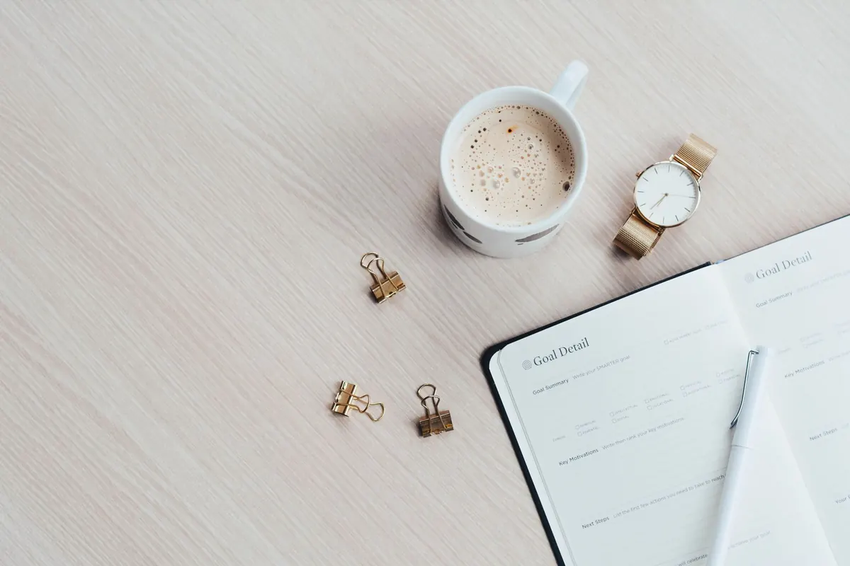Carnet de planification et café, en illustration de « coulisses de la vente d'articles portés »