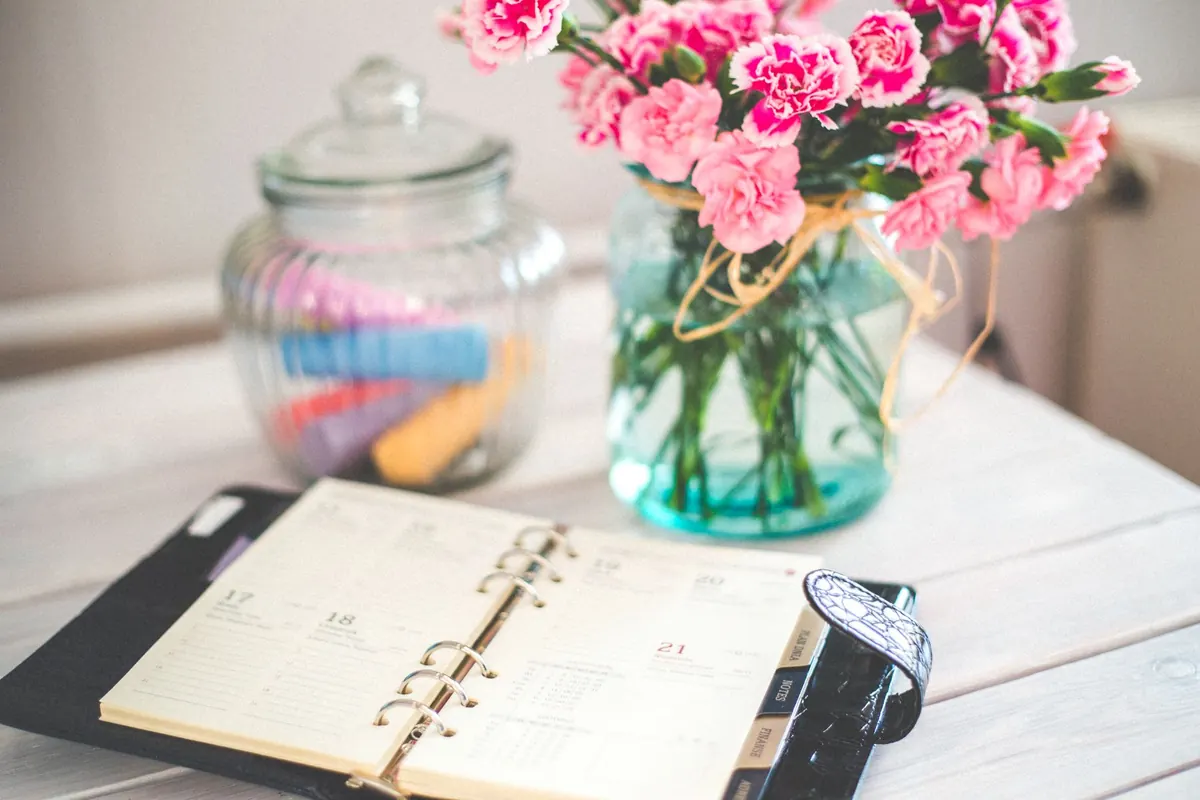 Agenda ouvert et bouquet de fleurs, en illustration de « premier achat de culottes usagées »