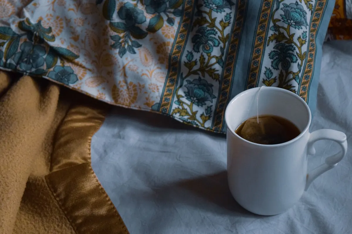 Mug de thé sur des draps fleuris, en illustration de « vendre des articles portés sur Etsy ou eBay »