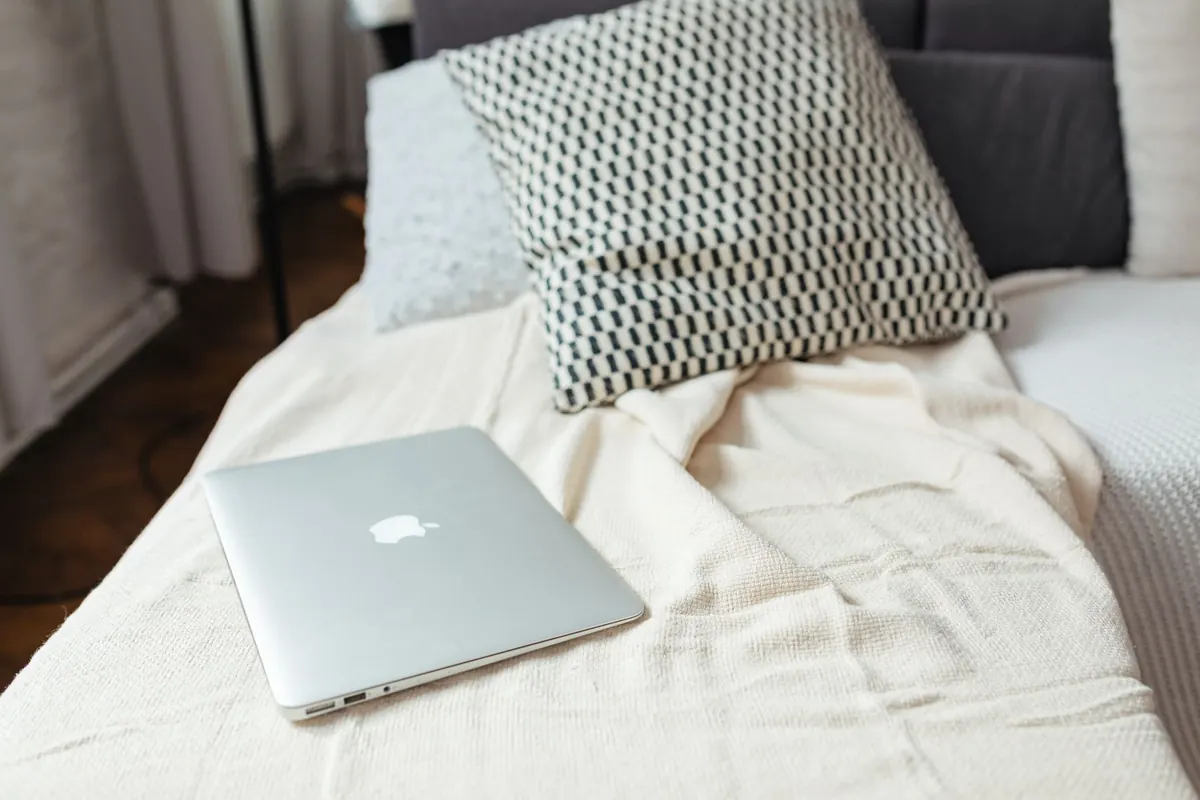 Ordinateur posé sur un lit, en illustration de « vendre des articles portés sur Etsy ou eBay »