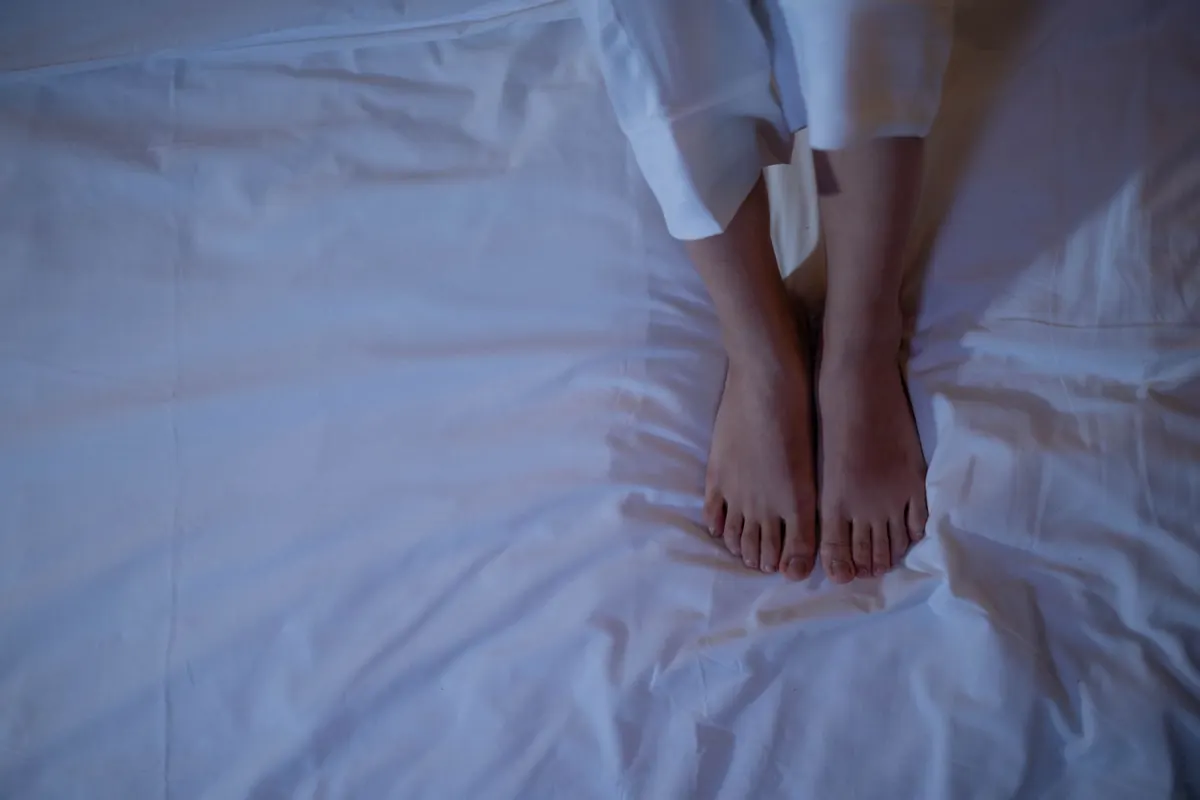 Pieds nus sur un drap bleuté, en illustration de « blog fétichisme des pieds »
