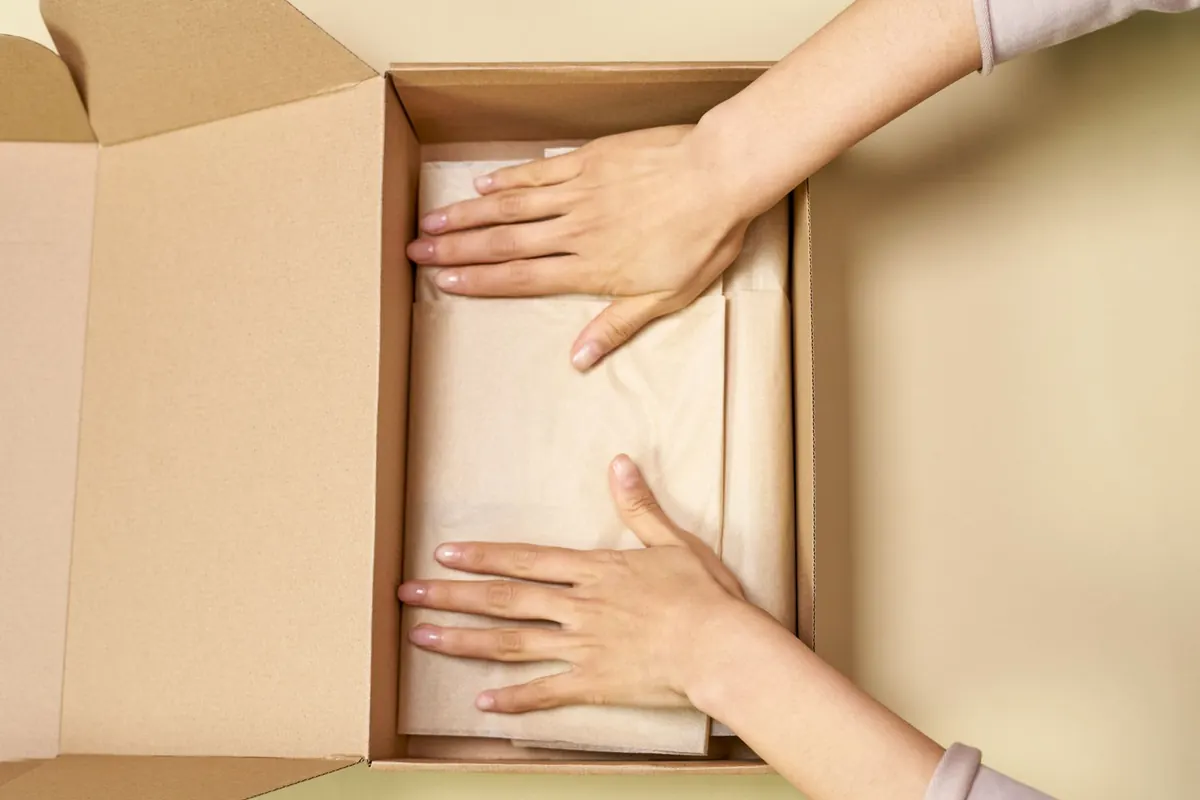 Mains fermant un colis, en illustration de « conseils pour devenir une vendeuse prospère »