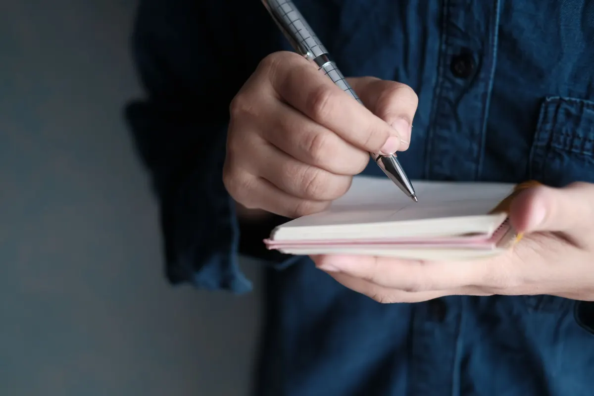 Main qui écrit dans un carnet, image d'illustration : démarrer son activité de vente de culottes