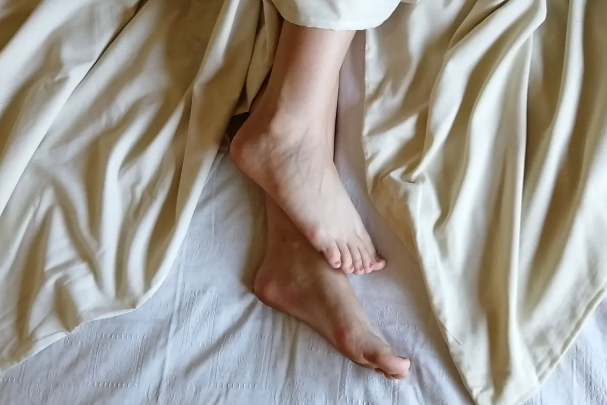 Pieds sur des draps crème, en illustration de « fétichisme des pieds chez la femme »