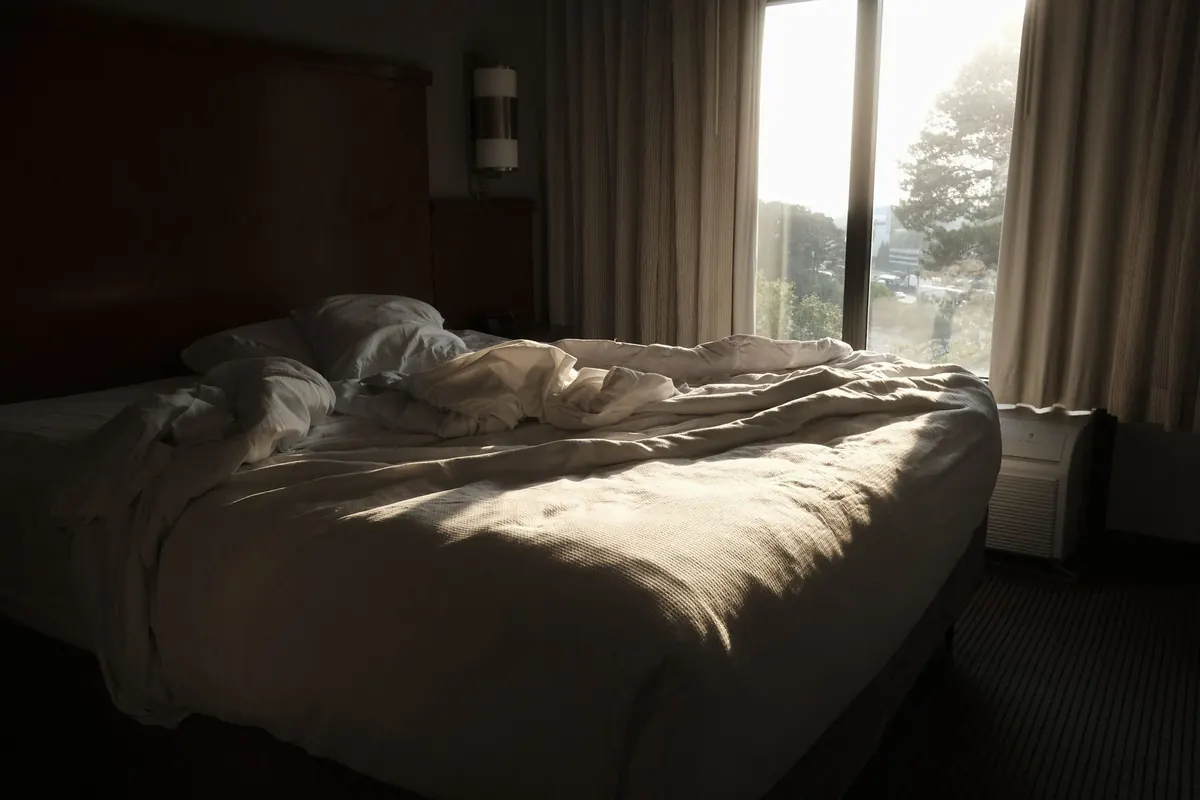 Lit défait dans une chambre lumineuse, en illustration de « pourquoi vendre des culottes usagées »