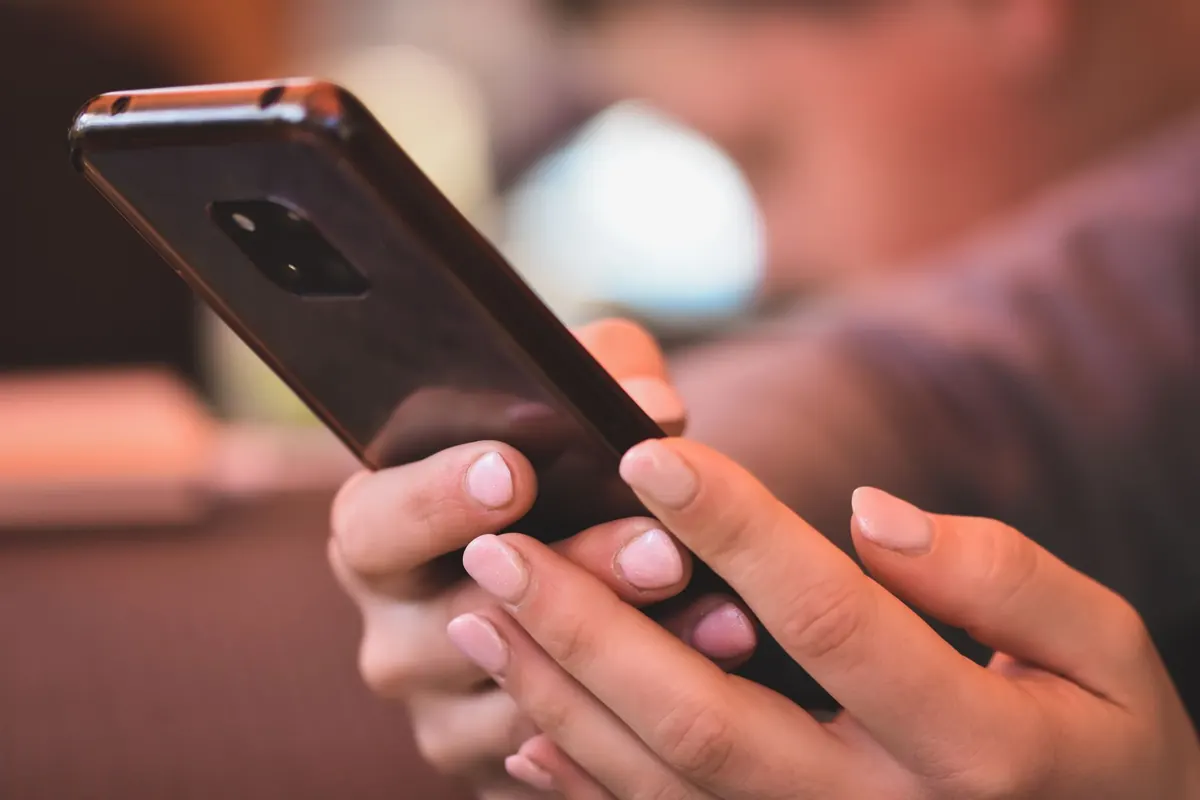 Mains tenant un téléphone, en illustration de « culotte portée personnalisée »