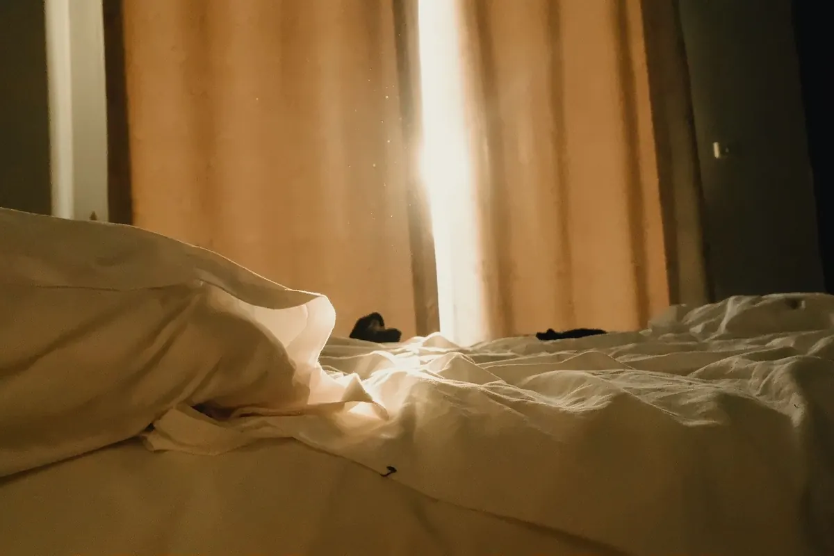 Draps défaits dans une lumière dorée, image d'illustration : combien de temps porter une culotte avant de la vendre