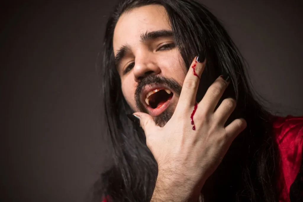 Portrait rapproché d'un homme en cosplay de vampire avec crocs et sang
