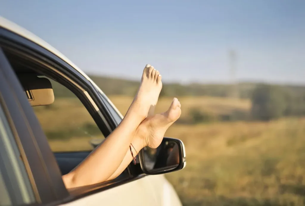 Femme pieds nus avec pédicure se détend dans une voiture, pieds croisés