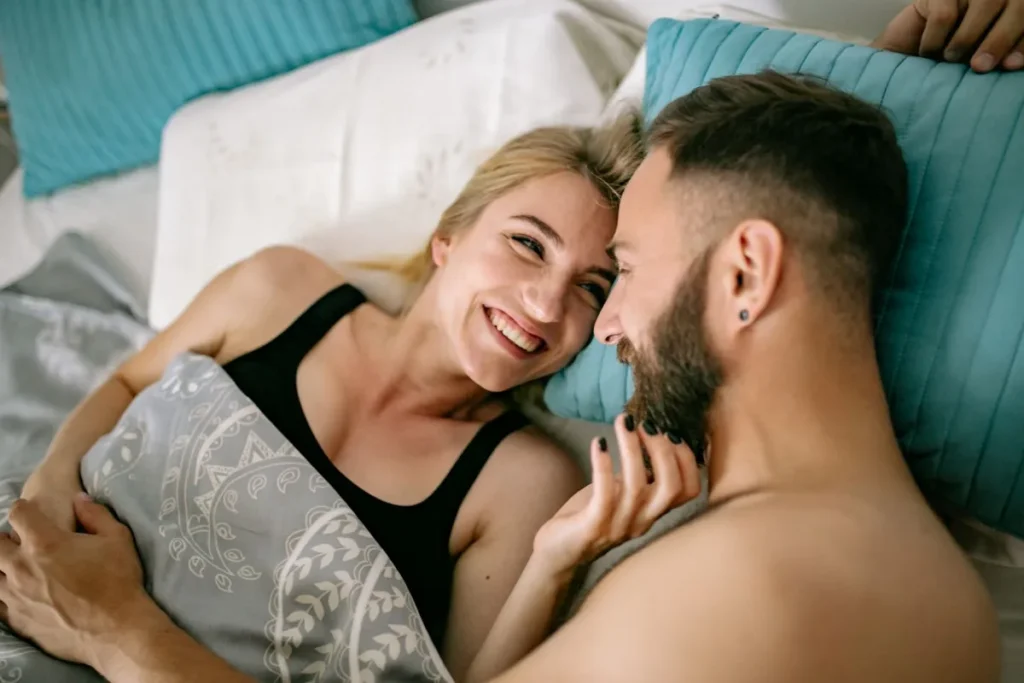 Couple joyeux se blottissant au lit, amour et intimité à la maison.