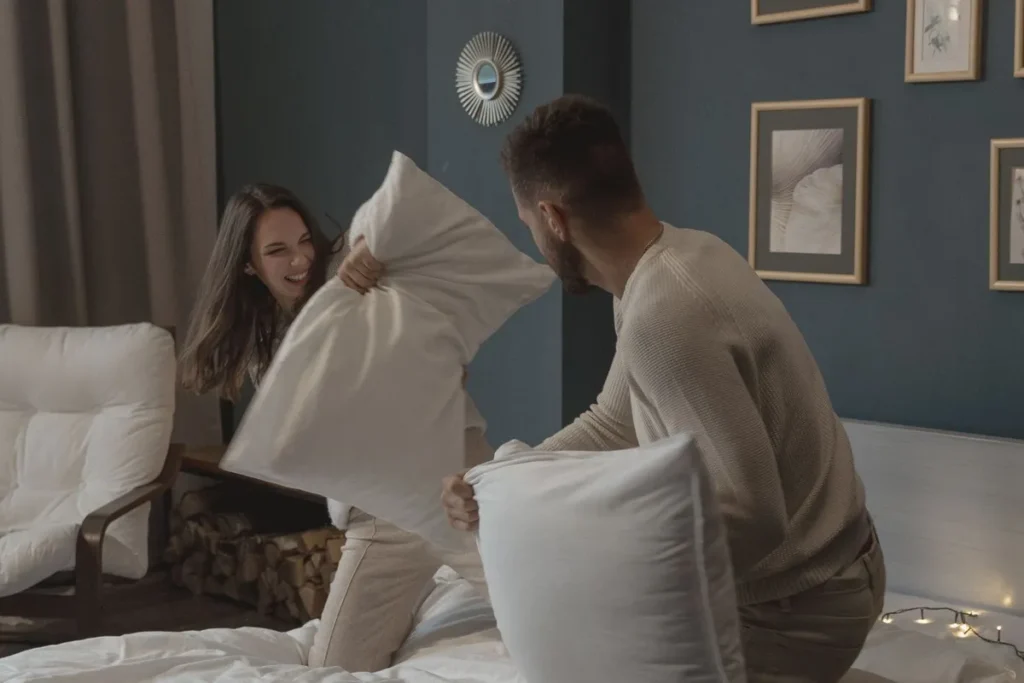 Un couple heureux s'amuse lors d'une bataille d'oreillers à la maison