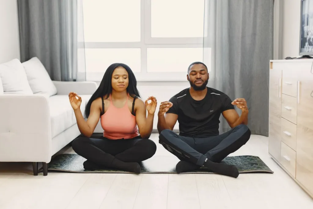 Un couple médite sur des tapis de yoga dans un salon lumineux