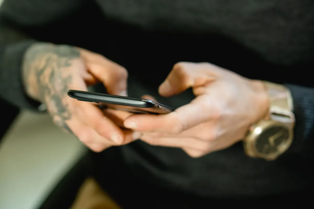 Mains tatouées et téléphone, en illustration de « photo culotte à vendre »