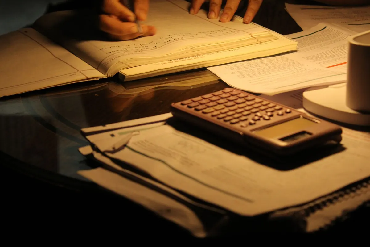 Calculatrice et papiers sous une lampe, en illustration de « vendre collants portés »
